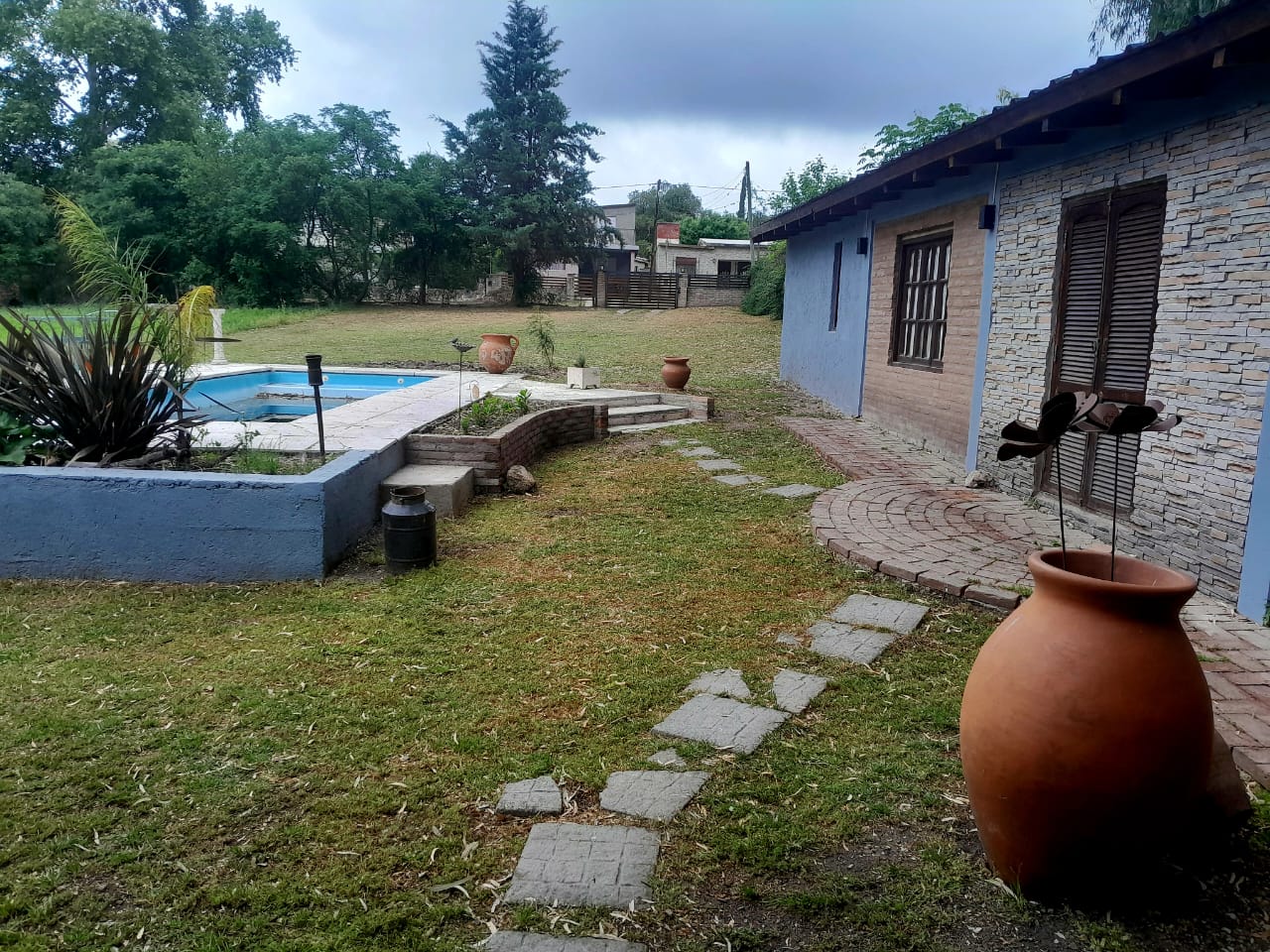 Jardín, pileta y casa de ladrillo de día